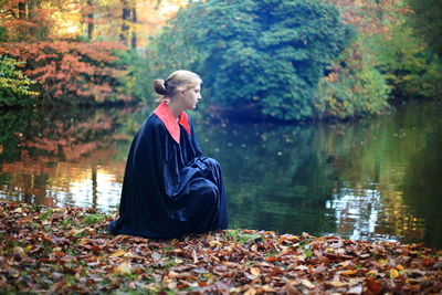 Woman sitting by lake during autumn