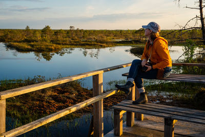 Woman admires a forest lake at sunset, a landscape of a raised bog