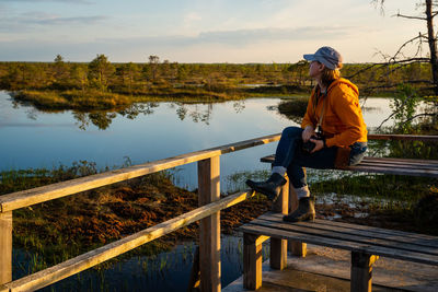 Woman sitting on bench by lake