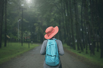 Rear view of woman walking on road amidst trees