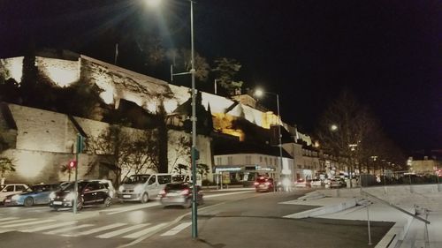 Road passing through illuminated city at night