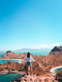 Rear view of woman looking at mountains against clear blue sky