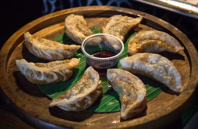 High angle view of hot deep fried gyoza served in the wooden plate with sauce