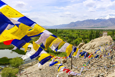 Various flags hanging on mountain against sky