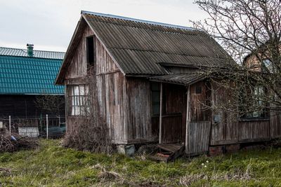 Old abandoned house by tree against sky
