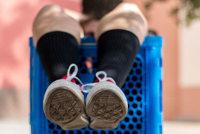 Low section of man sitting on blue shopping cart