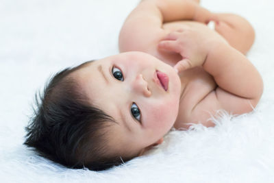 Portrait of cute baby boy lying on bed