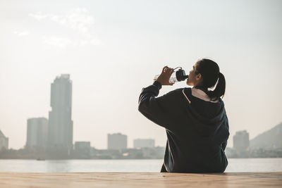 Man photographing against sky in city