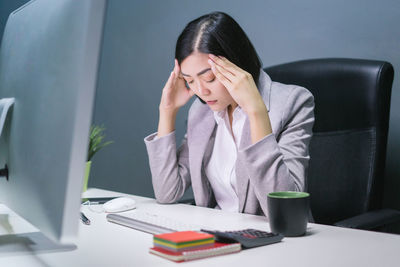 Young woman using mobile phone while sitting on table