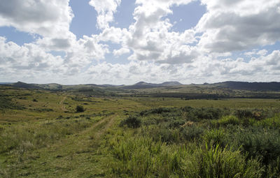 Scenic view of grassy field and mountains against sky