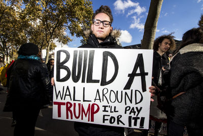 People standing by sign against trees