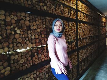 Portrait of young woman standing against brick wall