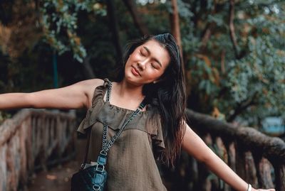 Portrait of woman standing against tree