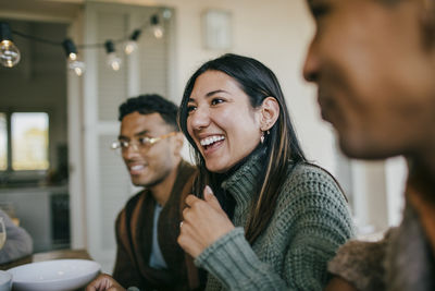 Cheerful woman sitting with male friends at dining table in patio