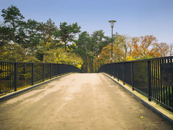 Footbridge amidst trees against sky