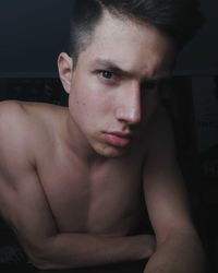 Portrait of shirtless young man in dark