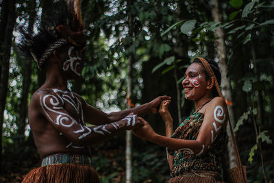 Smiling young woman against trees in forest