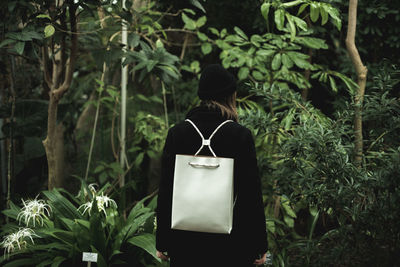 Rear view of woman standing with backpack against trees