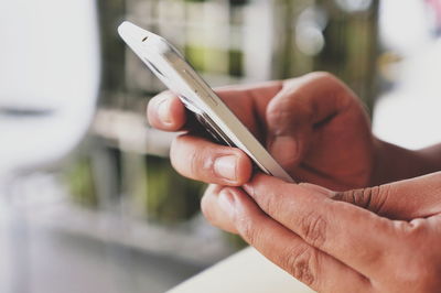 Close-up of person holding mobile phone on table 