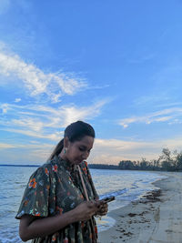 Woman standing at beach against sky