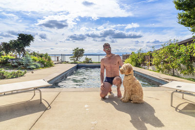 Portrait of man sitting in swimming pool against sky