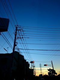 Low angle view of electricity pylon against blue sky