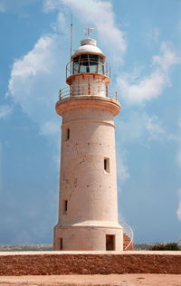 Low angle view of lighthouse by building against sky