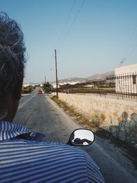 Rear view of woman on road against clear sky