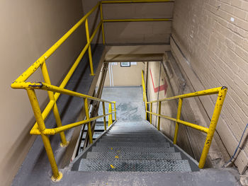Symmetrical view looking down an industrial stairwell with bright yellow railings