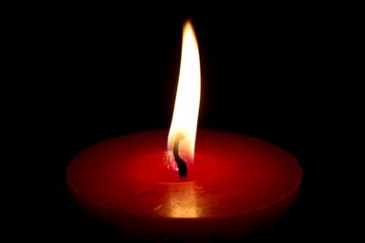 Close-up of lit candle in dark room