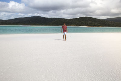 Rear view of man standing on beach against sky