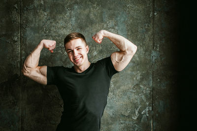 Close-up portrait of muscular man flexing muscles by wall