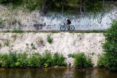 Rear view of man riding bicycle on lake