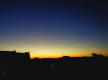 Low angle view of silhouette buildings against clear sky