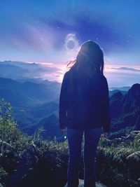 Rear view of woman looking at mountains against sky