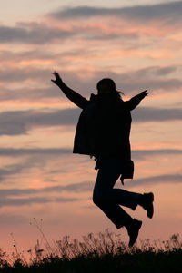 Silhouette boy against orange sky during sunset