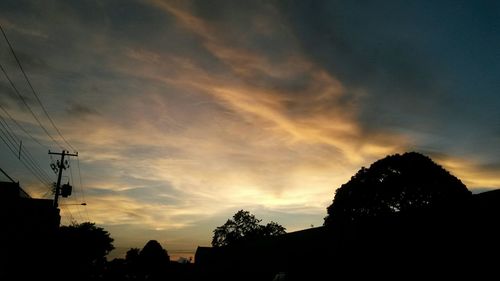 Low angle view of silhouette trees against cloudy sky