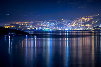 View of illuminated community on mountain by river at night