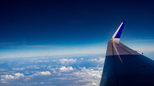 Airplane flying over cloudscape against blue sky