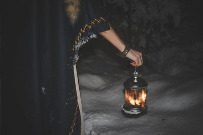 Midsection of woman holding illuminated glass