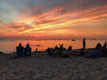 Silhouette people at beach against sky during sunset