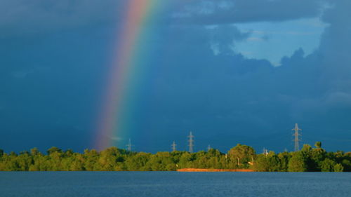 Scenic view of rainbow over lake against sky