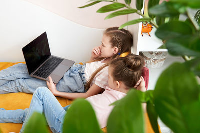 Sisters using laptop while lying in bed