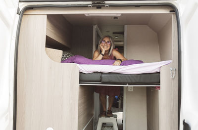 Happy woman with gray hair leaning on bed of motor home