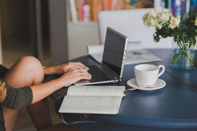 Midsection of woman using laptop at table