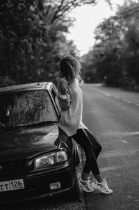 Woman standing by car on road