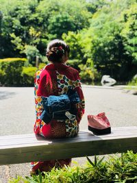 Rear view of woman in kimono sitting on bench