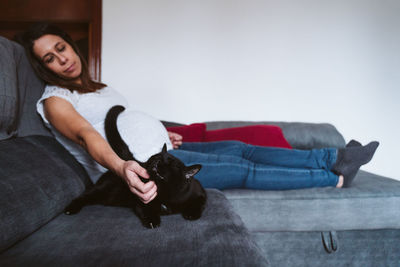 Pregnant woman spending leisure time with cat at home