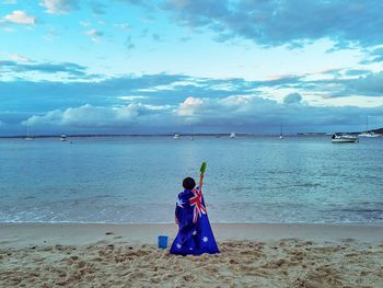 Rear view of woman sitting on beach