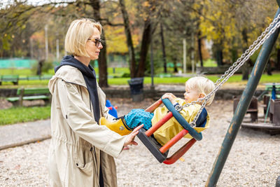 Portrait of young woman swinging in playground